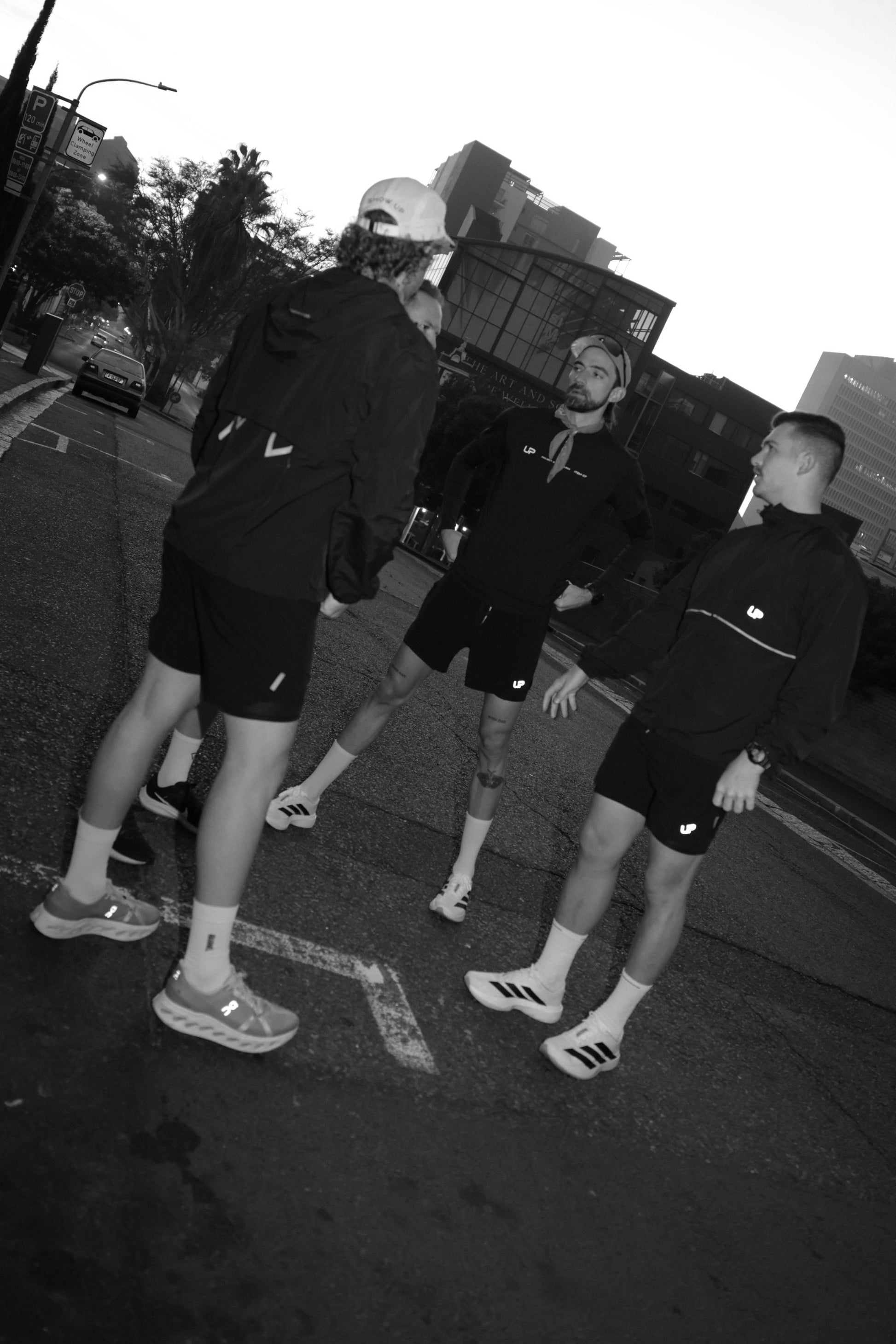 Four men wearing UP Active prepping for a run. They are wearing running shorts and a windbreaker.