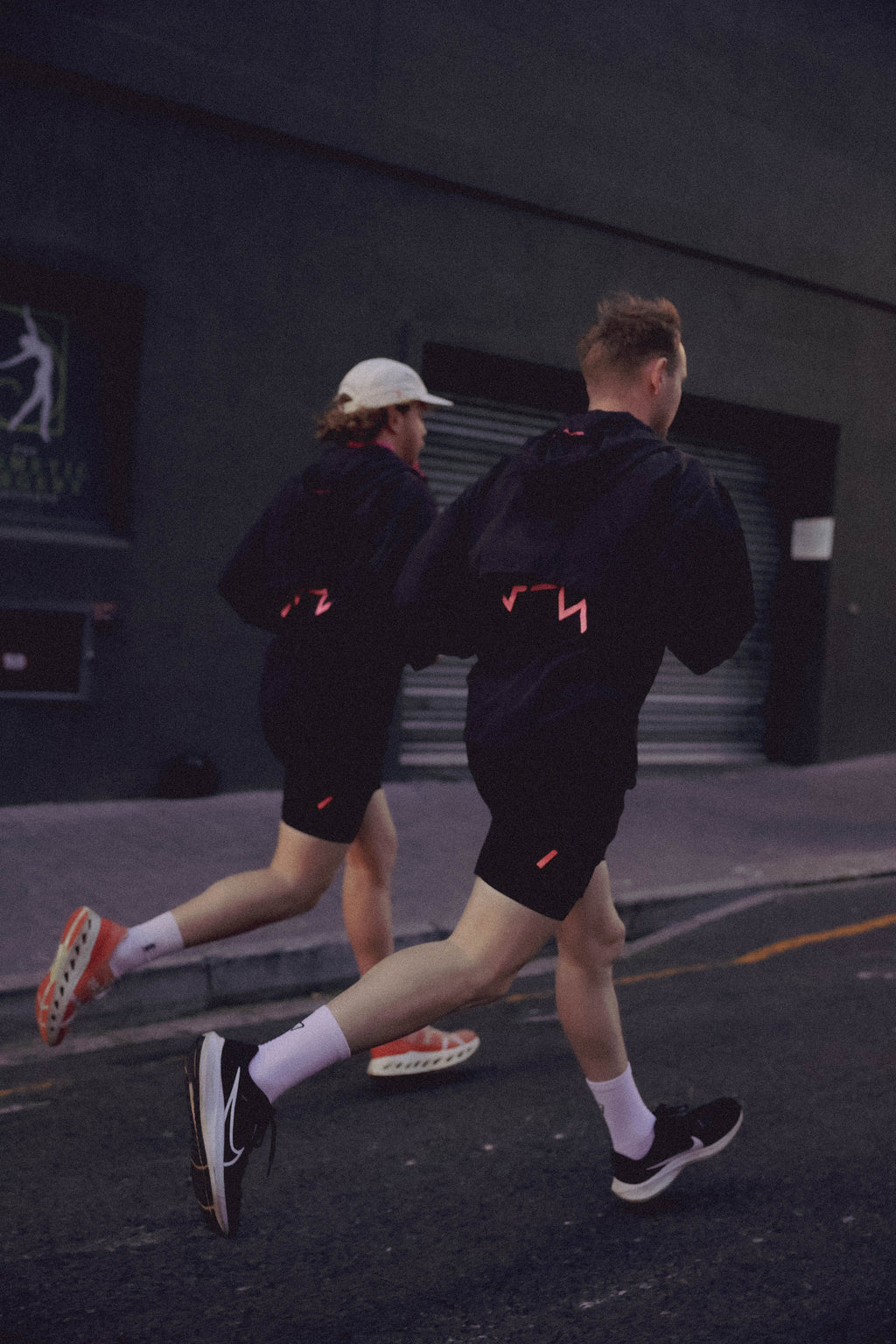 Two people running on a street at night wearing UP Active Mens Shorts and Windbreaker