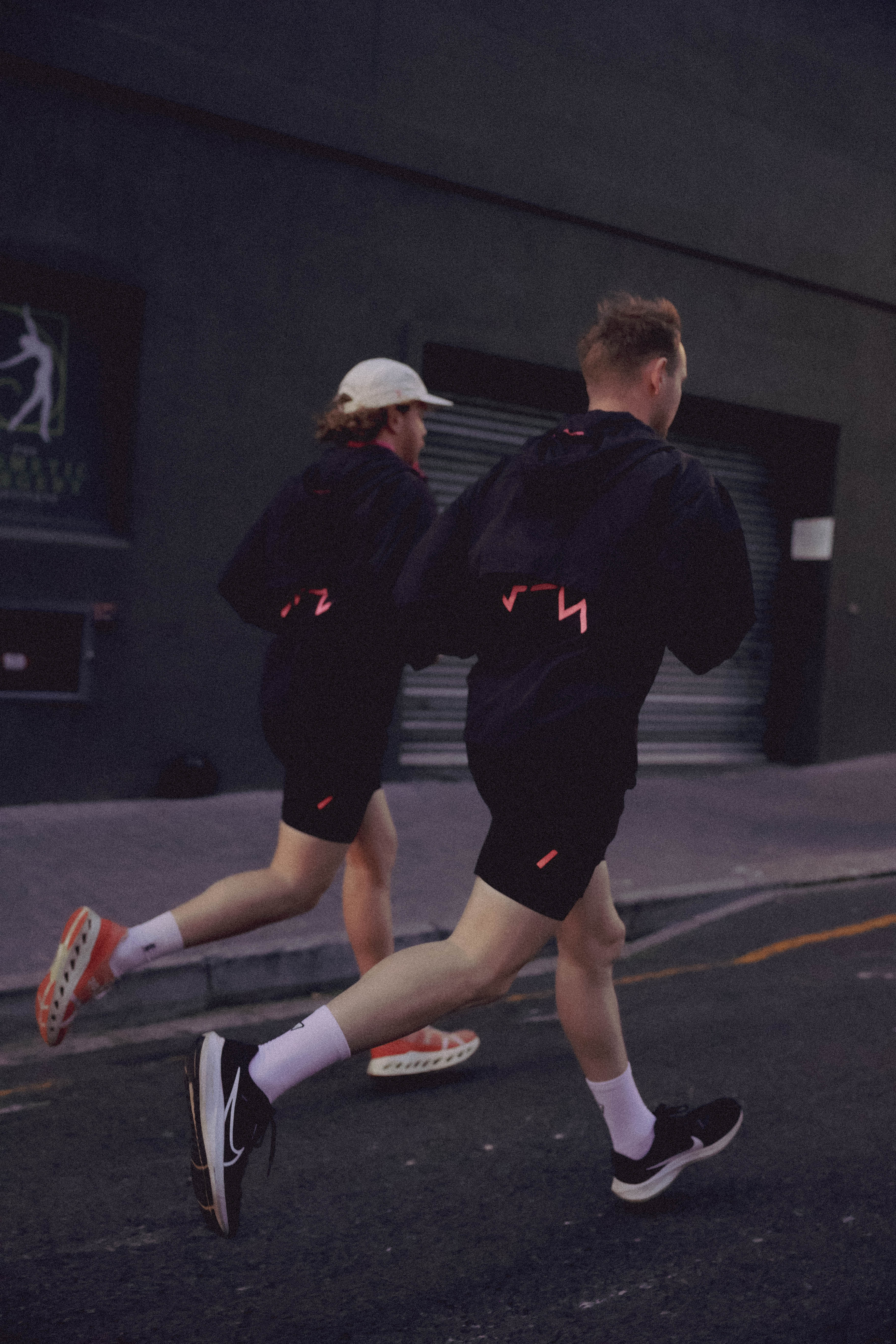 Two people running on a street at night wearing UP Active Mens Shorts and Windbreaker
